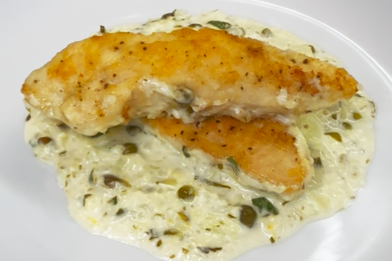 two chicken cutlets on top of lemon caper sauce