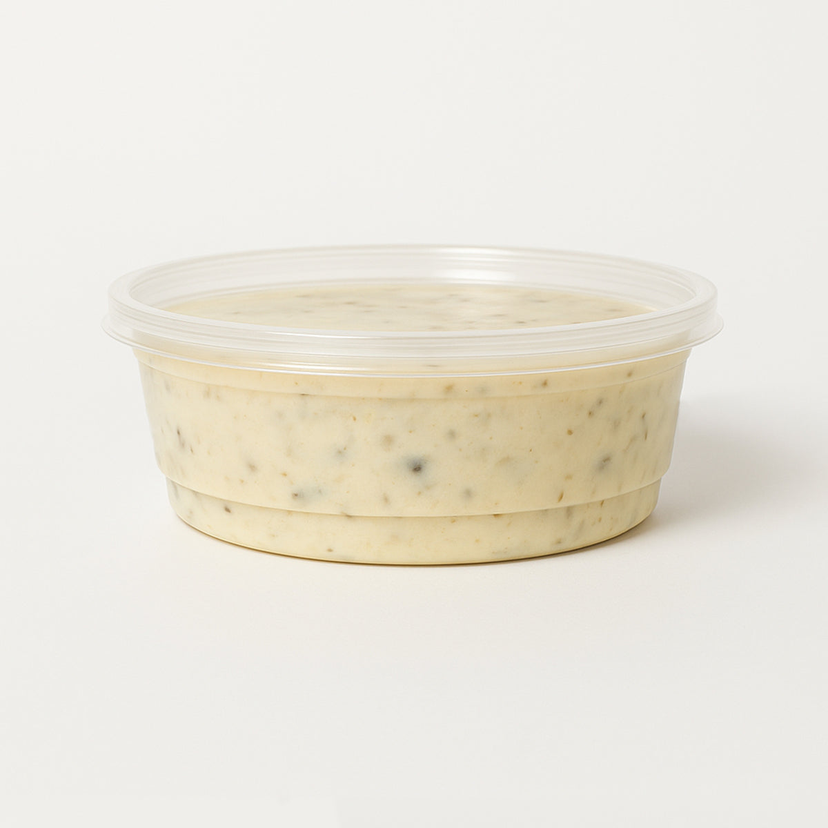 Container of lemon caper sauce on a white background