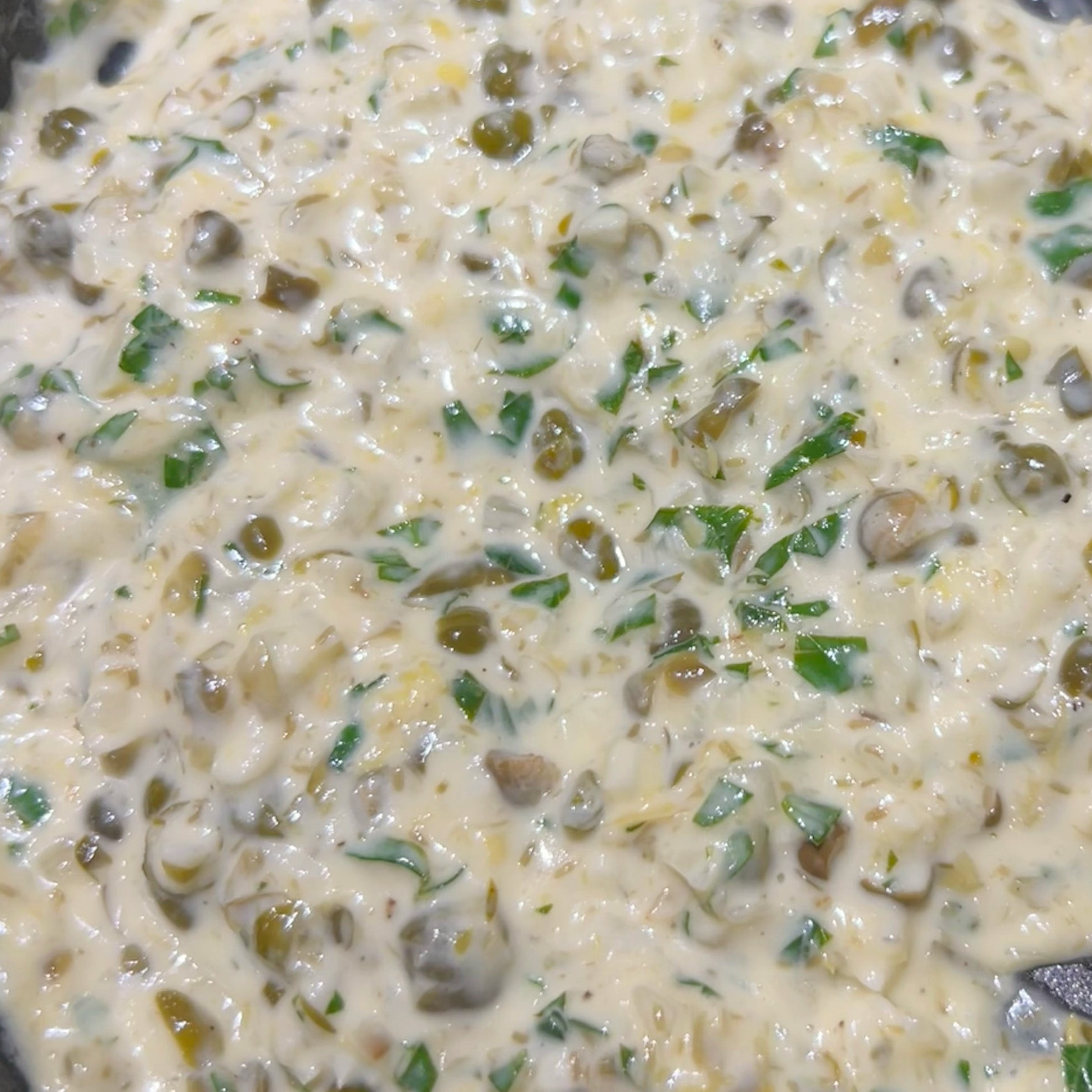 Mixture of creamy lemon caper sauce with green herbs and capers