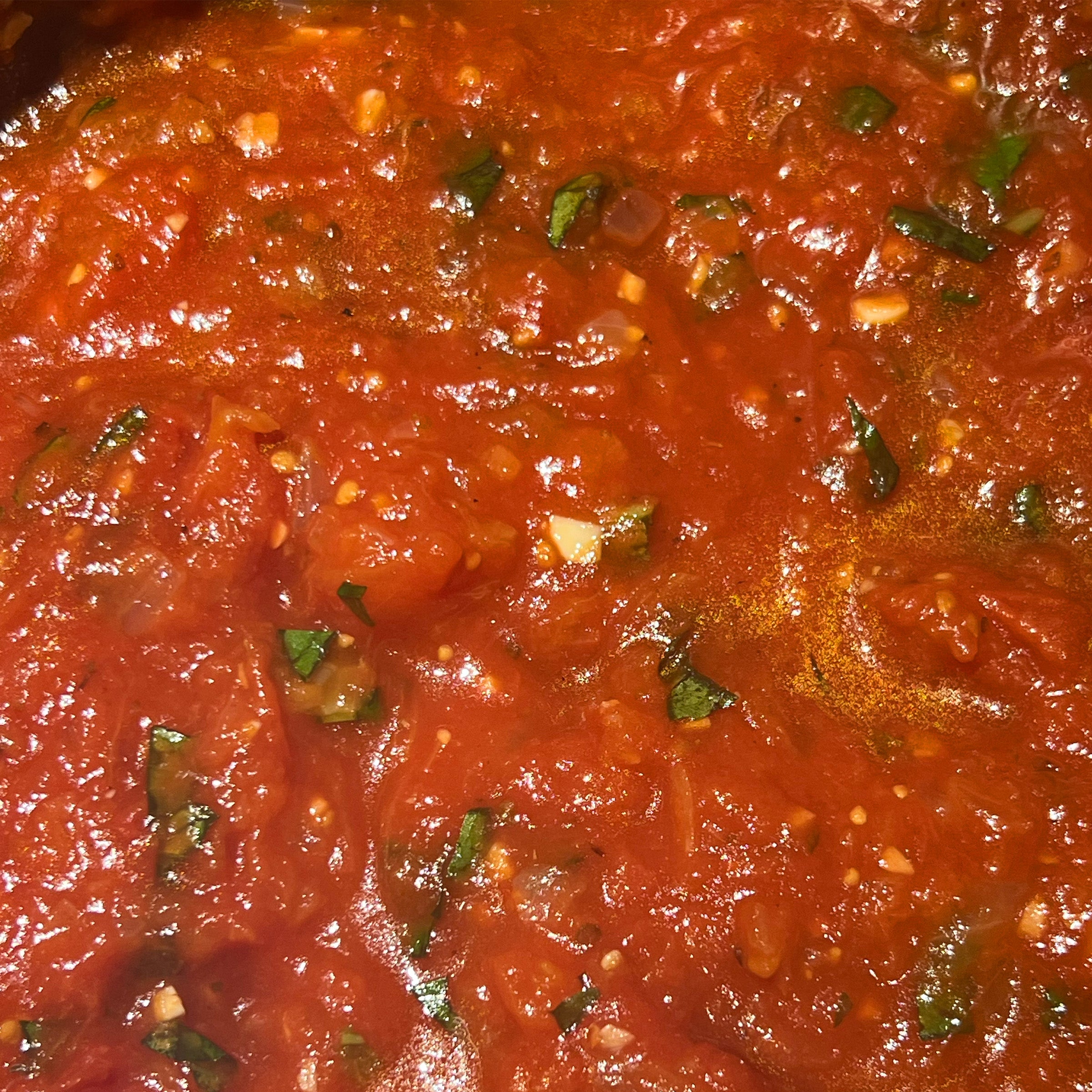 Close-up of red tomato sauce with green herbs