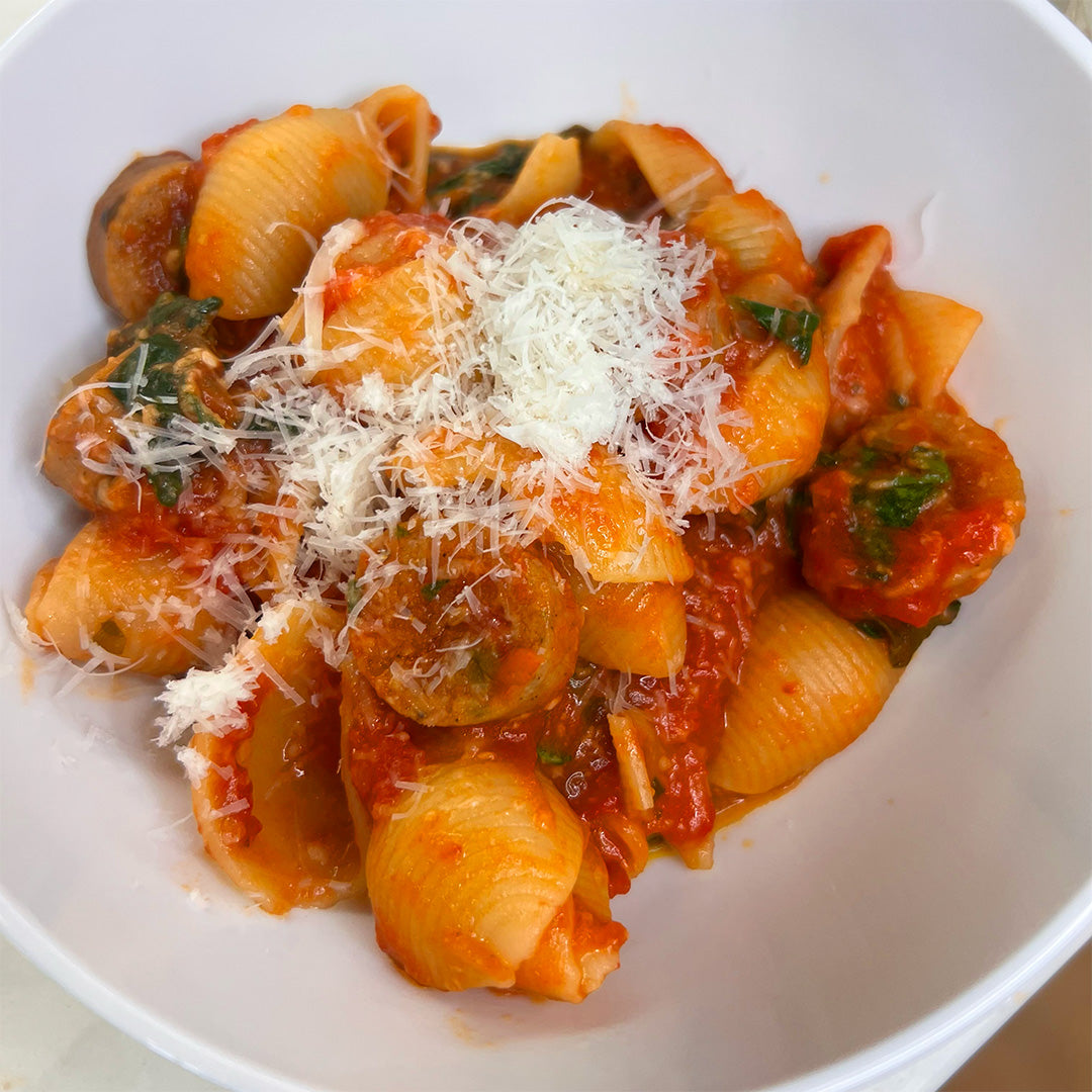 Pasta dish with tomato sauce and spinach in a white bowl