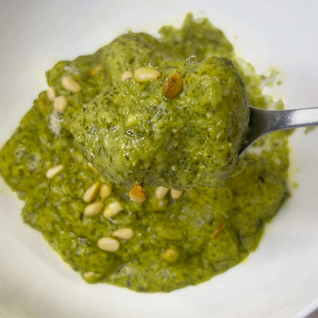 Green pesto with pine nuts on a white plate